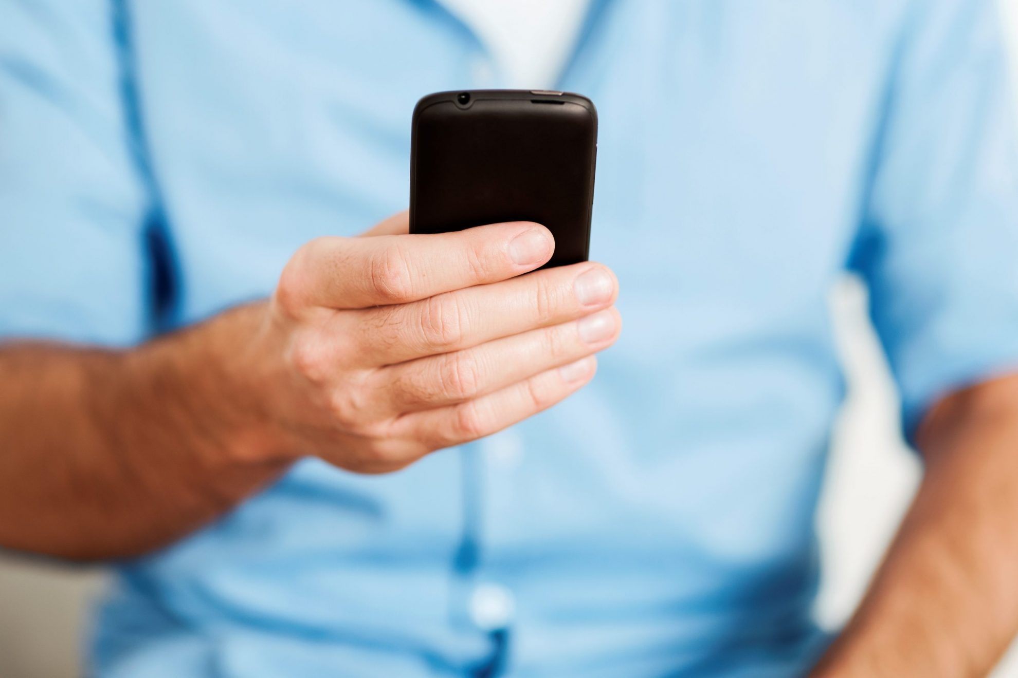 Photo of man holding smartphone illustrates blog: "3 Holiday Scams You Should Be Aware Of"