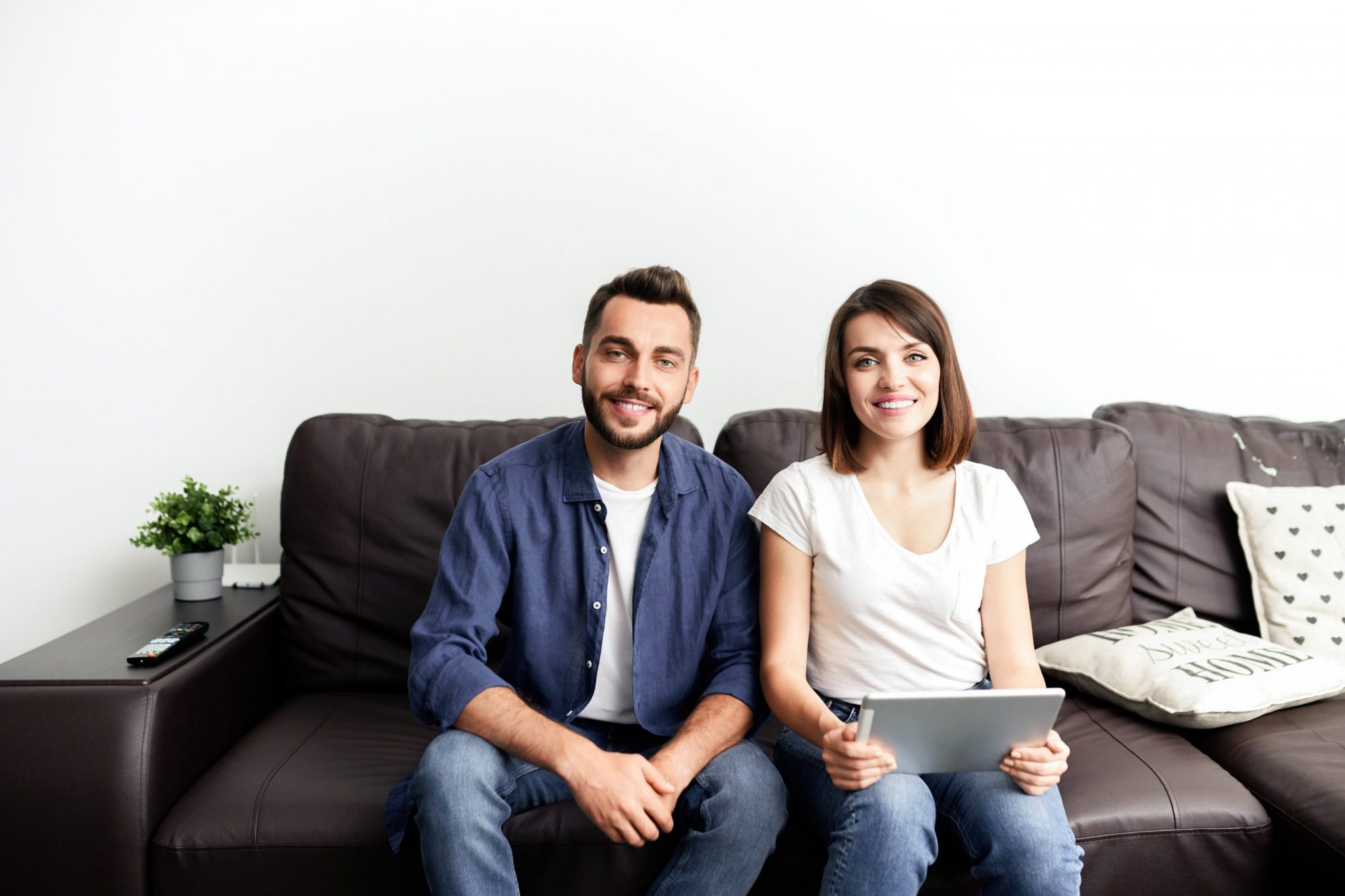 Photo of smiling couple sitting on couch illustrates blog: "2022 Tax Season: How to Avoid Penalties and Interests "