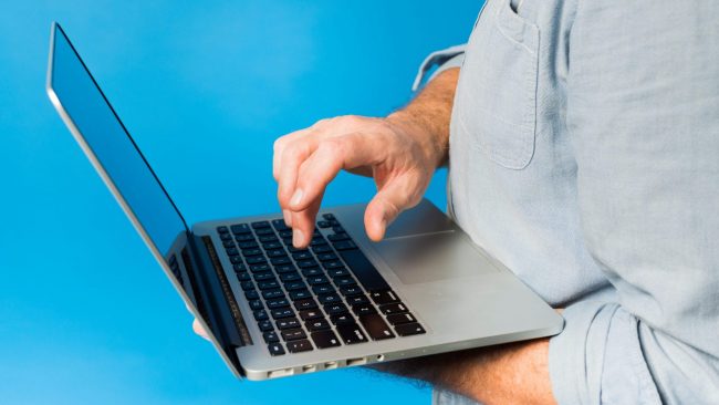 Photo of man with laptop illustrates blog: "How to Check the Status of a Refund"