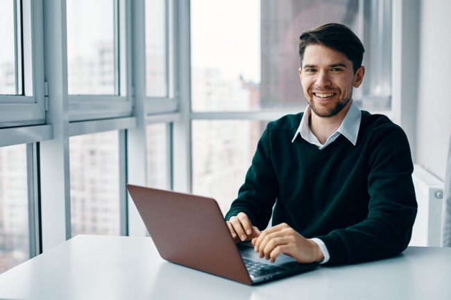 Photo of man sitting at desk with laptop illustrtes blog: "What To Do If You Couldn’t File Your Taxes Before April 18"