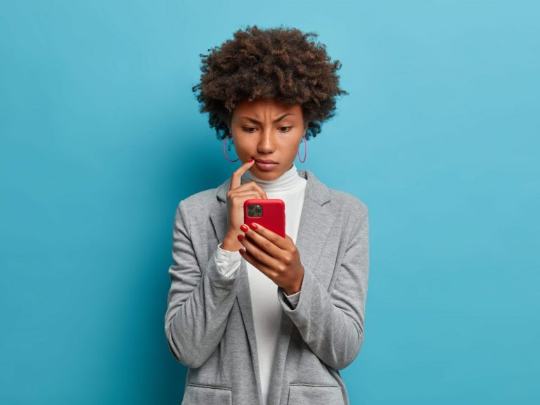 Photo of woman looking at phone illustrates blog: "Don’t Fall for These Tax Season Scams"
