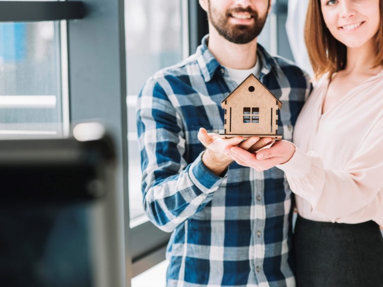 Photo of couple holding scale model of a house illustrates blog: "5 Tips for Affordable Homeowners Insurance in California"