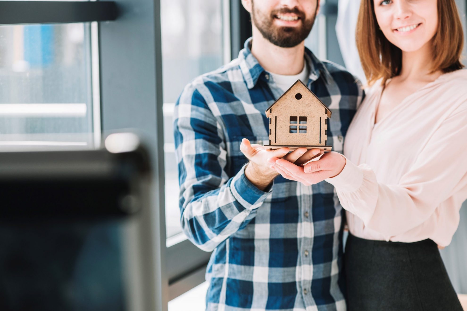 Photo of couple holding scale model of a house illustrates blog: "5 Tips for Affordable Homeowners Insurance in California"