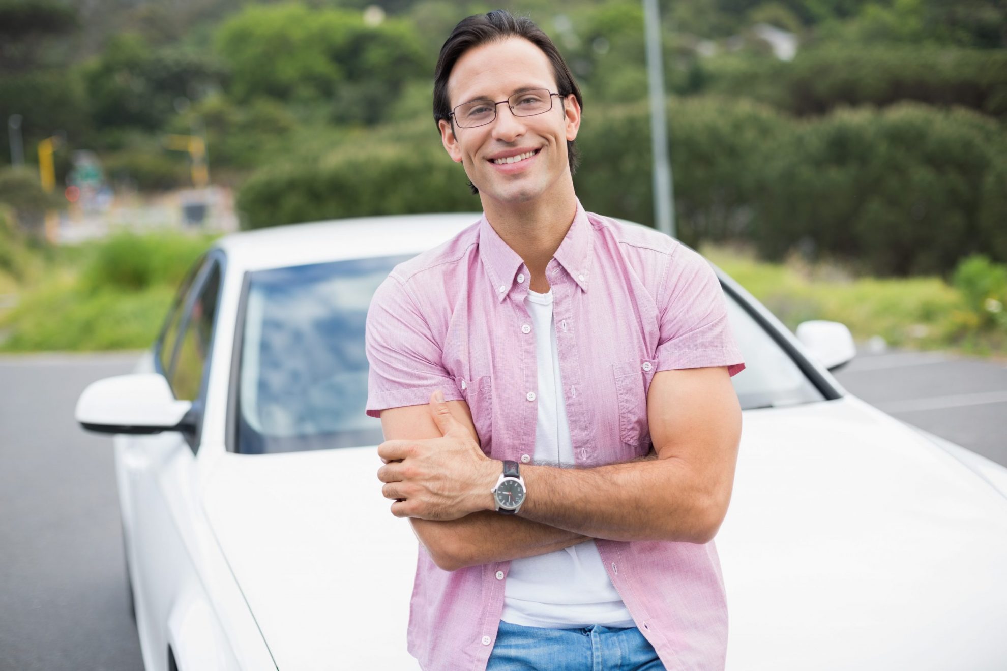 Photo of smiling man leaning against car illlustrates blog: "What Is The IRS Mileage Rate for 2022?"