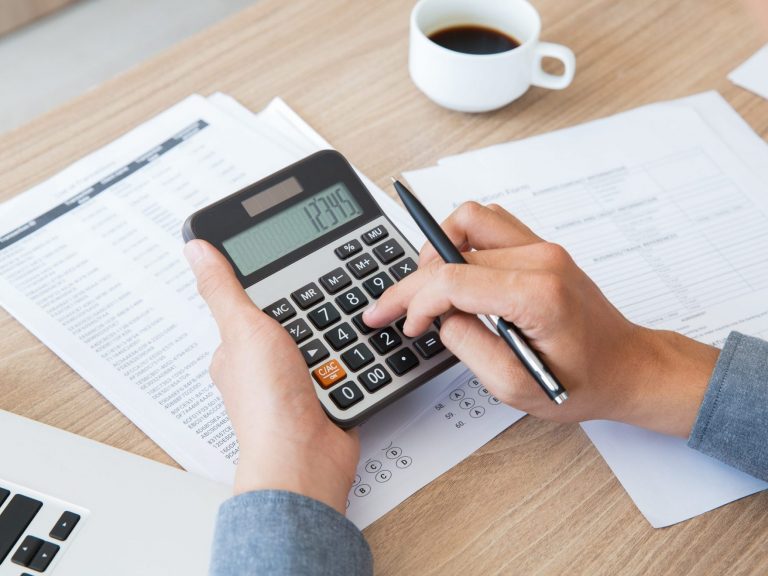 Photo of person holding calculator illustrates blog: "When Is Tax Day Going To Be in 2023?"