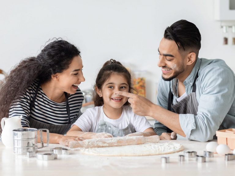 Family of mother, father, and daughter playing in kitchen illustrates blog "How Will the Child Tax Credit Affect 2022 Taxes?"