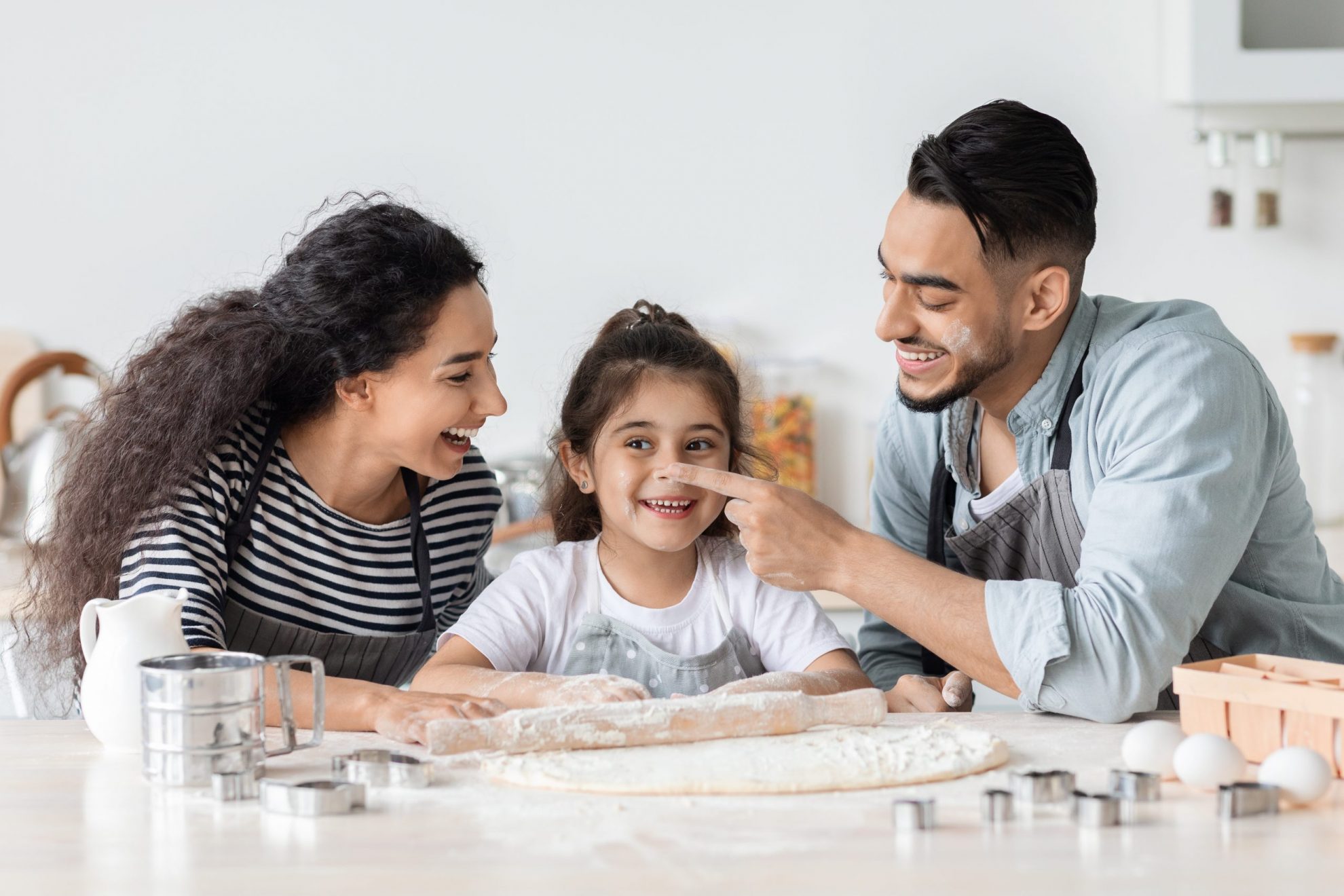 Family of mother, father, and daughter playing in kitchen illustrates blog "How Will the Child Tax Credit Affect 2022 Taxes?"