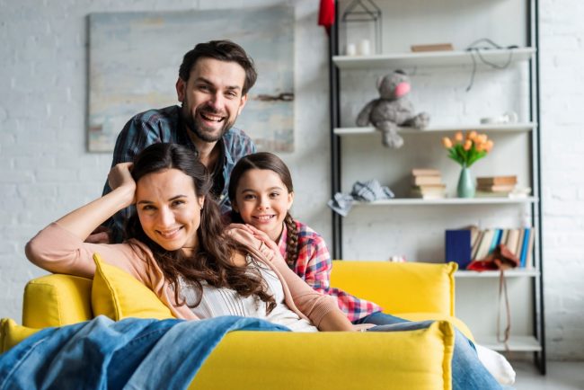 FamilyLivingRoom3 Photo of family in living room illustrates blog: "Is Home Insurance Mandatory When You Take Out a Home Loan?"