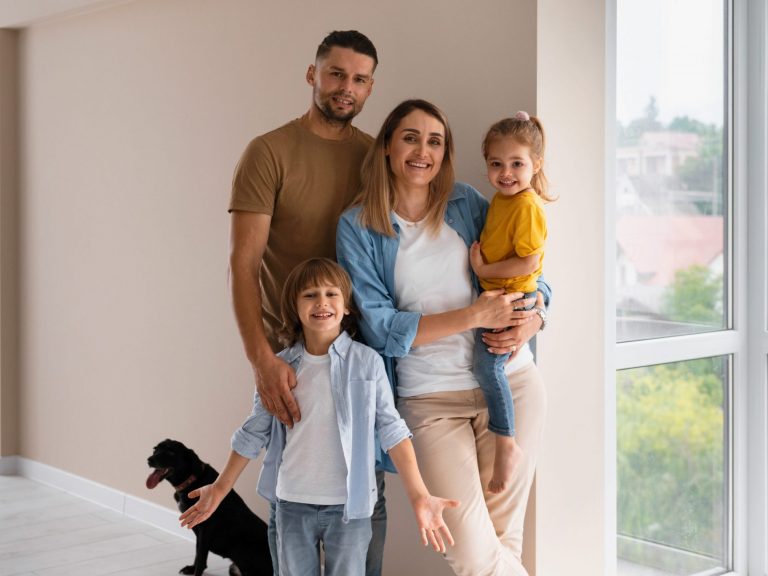 Homeowners3 Family of four with dog by window illustrates blog "How Much Home Insurance Do I Need?"
