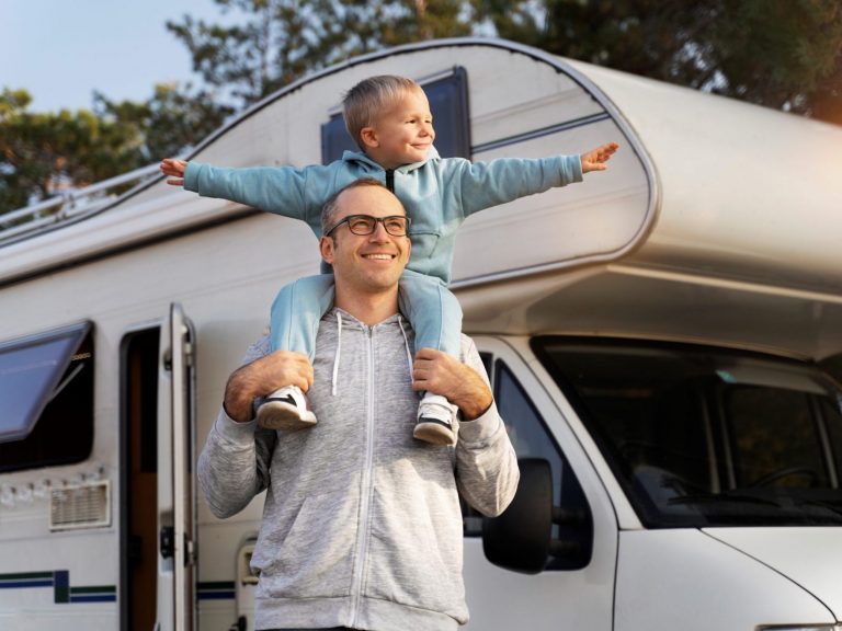 RVInsurance3 Man carrying child on his shoulders with RV in the background