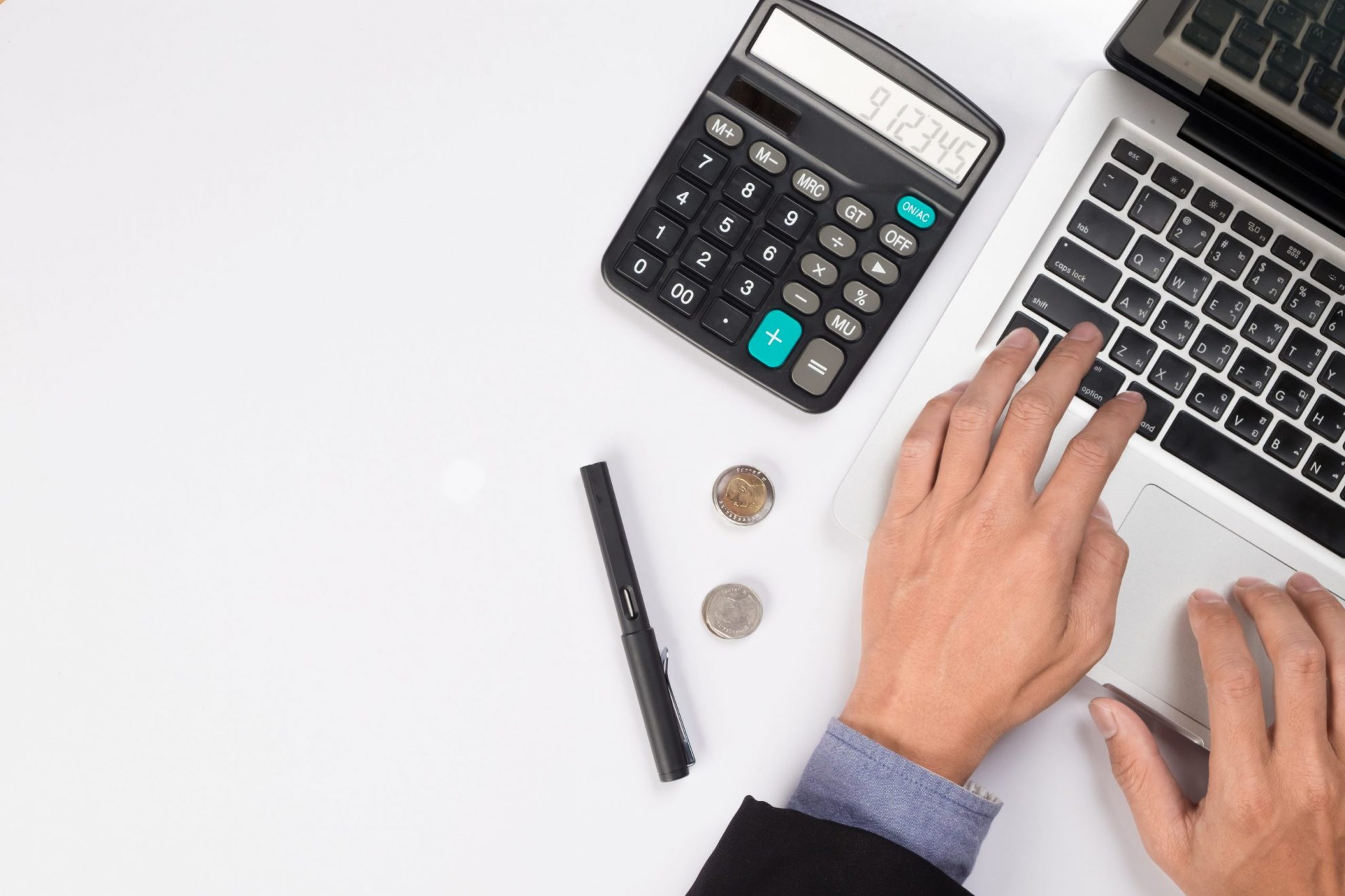 Closeup of person typing on laptop with calculator by their side illustrates blog "Tax Season Tips – How to Make the Process a Little Easier"