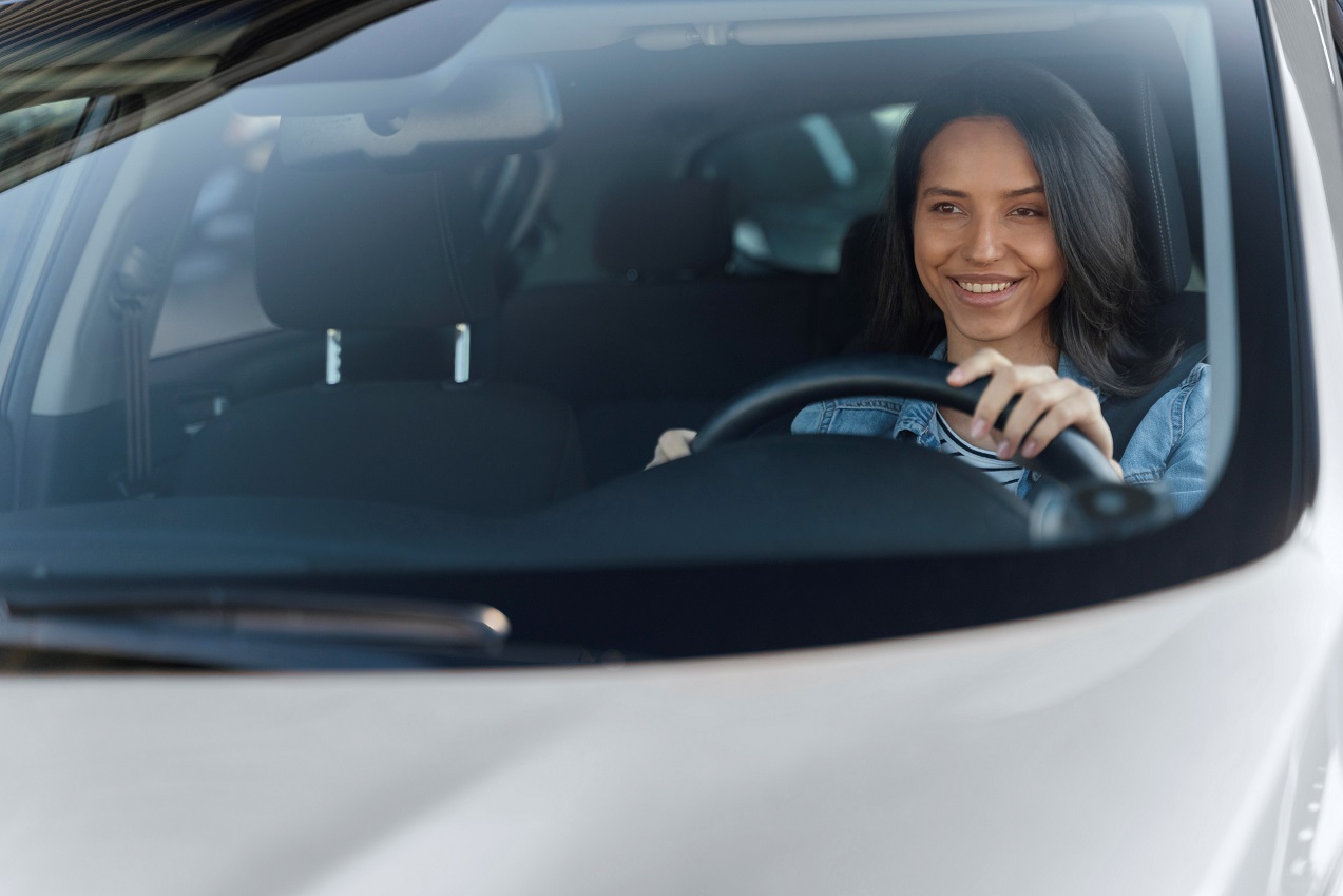 Smiling woman at the wheel of her car illustrates blog "How Much Auto Insurance Do I Need?"
