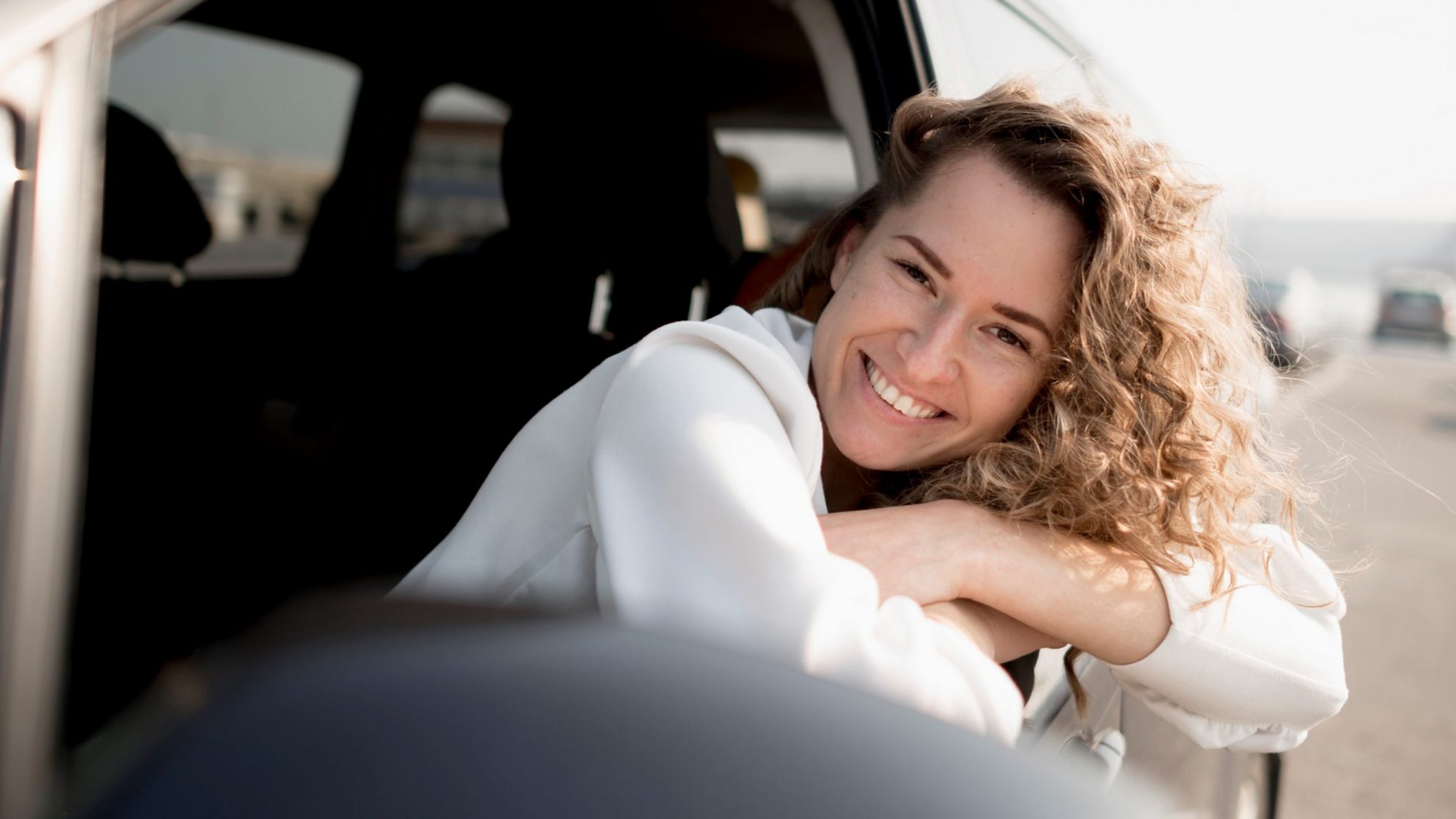 WomanSmilingCar Woman leaning against car window illustrates blog "5 auto insurance tips"