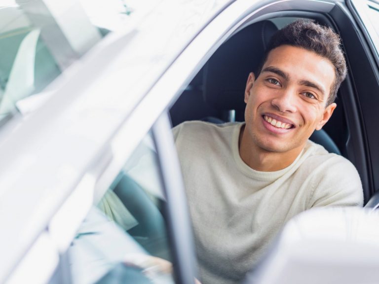 Man smiling in car illustrates blog "4 Tips to Protect Your Car's Paint"