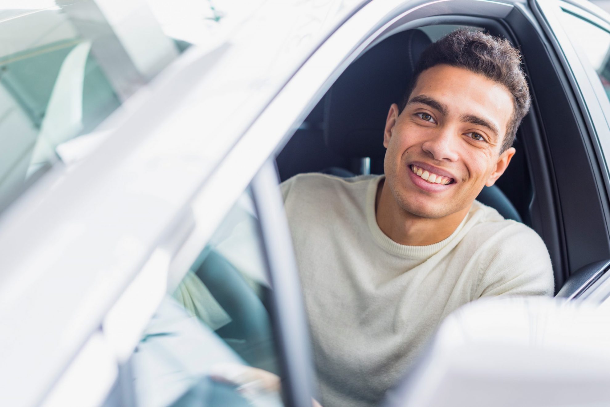 Man smiling in car illustrates blog "4 Tips to Protect Your Car's Paint"