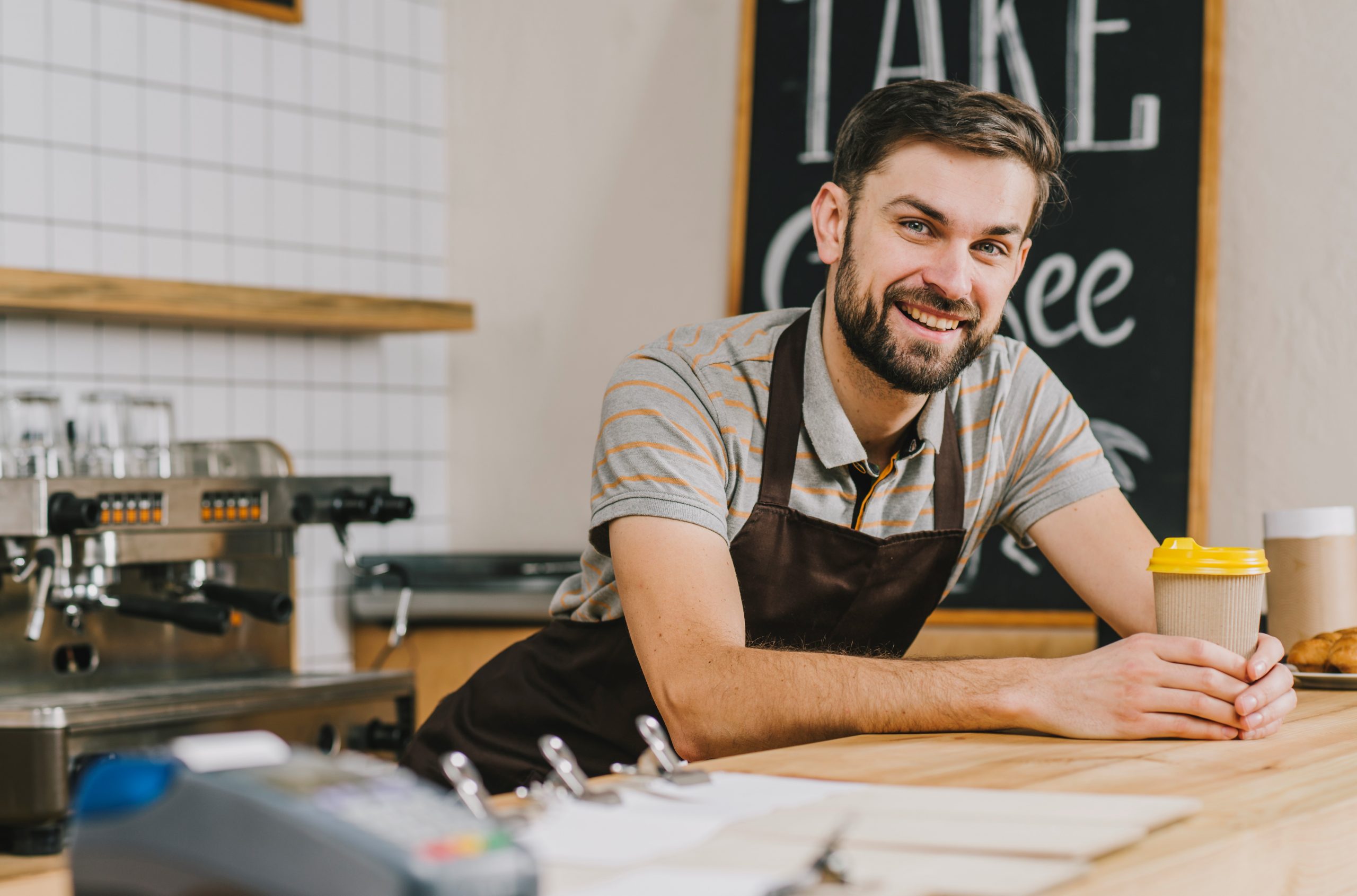 sole-prorprietorship-FP Man smiling behind café bar illustrates blog "What Is a Sole Proprietorship?"