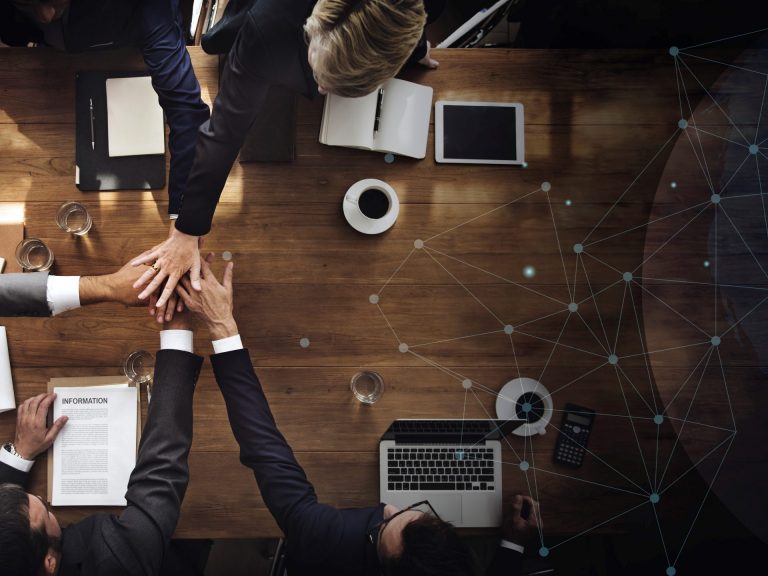 Aerial view of a business team People in business attire putting hands together illustrate blog "What Is a C Corporation? "