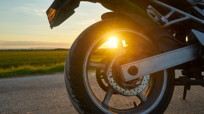 Closeup shot of a motorcycle on a sunset background Closeup of rear motorcycle tire illustrates blog "How Much Motorcycle Insurance Do I Need?"