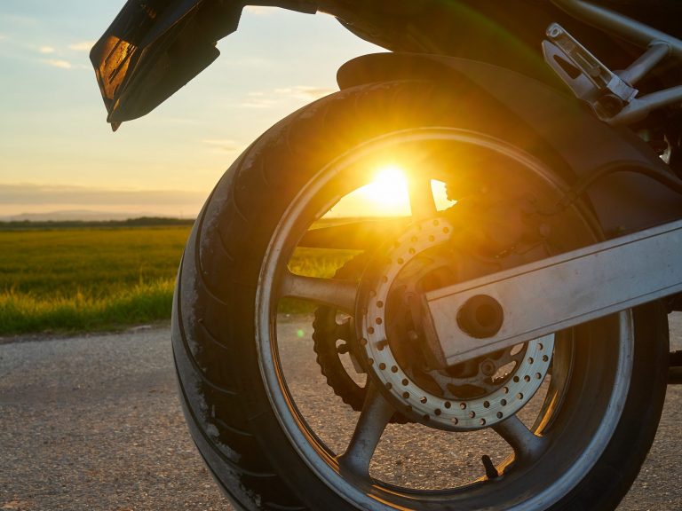 Closeup shot of a motorcycle on a sunset background Closeup of rear motorcycle tire illustrates blog "How Much Motorcycle Insurance Do I Need?"