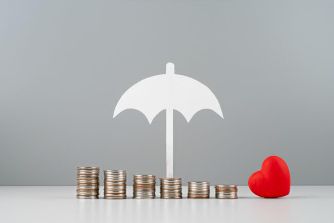2149191400 Stacked coins with umbrella and heart symbolizing bundle home and auto insurance protection