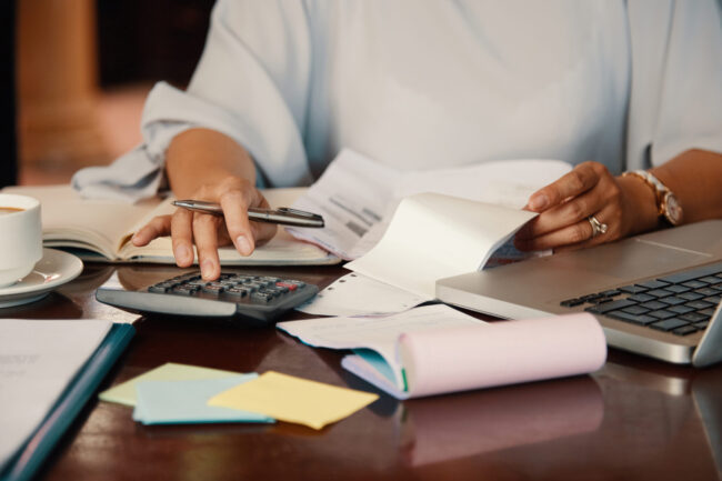 Entrepreneur working with bills Person reviewing tax return documents with labeled insurance folders (health, auto, home, business)