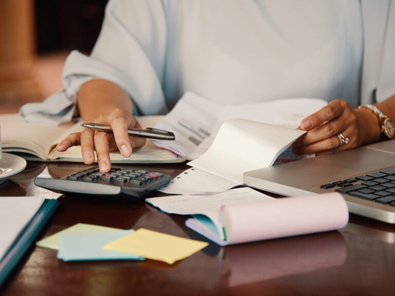 Entrepreneur working with bills Person reviewing tax return documents with labeled insurance folders (health, auto, home, business)